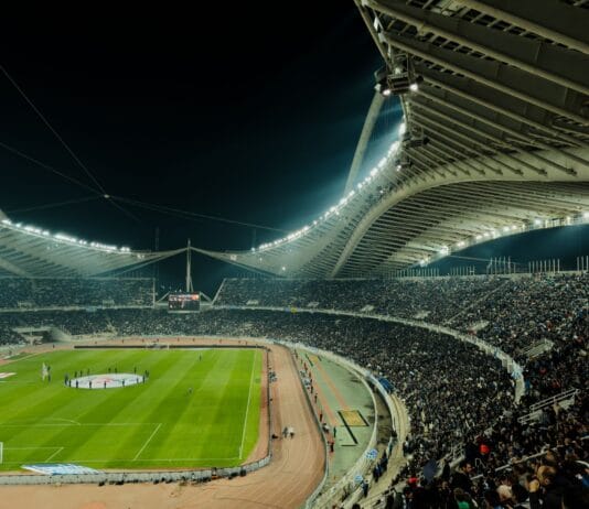 Zapełniony stadion piłkarski oświetlony nocą podczas meczu